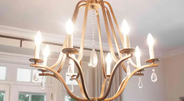 A golden chandelier with crystal drops hangs from the ceiling, illuminating the dining room. The dining room chandelier height is perfect for the space.