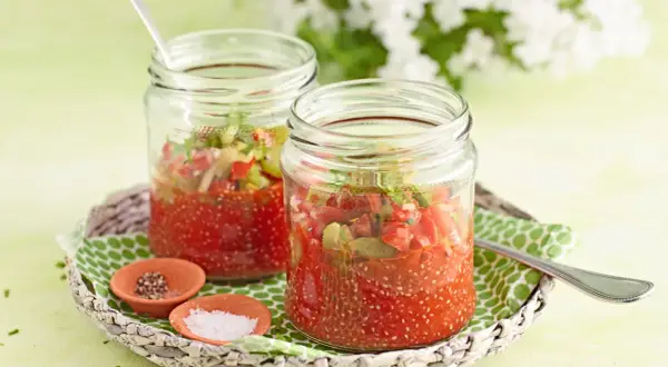 Zwei Gläser mit Tomaten-Chiasamen-Mischung, inspiriert von gesunden Chiasamen Rezepten. Daneben kleine Schälchen mit Salz und Pfeffer.