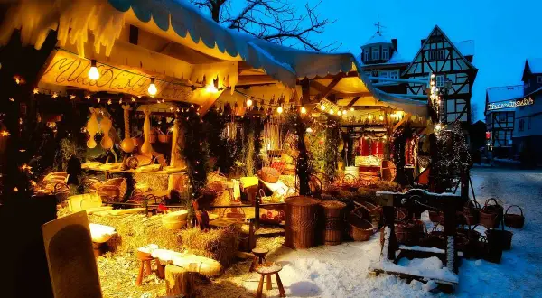 Winterliche Kirmes Gummersbach: Ein festlich beleuchteter Stand mit Körben und Holzwaren im Schnee.