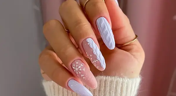 Manucure d'hiver avec des flocons de neige et un motif de pull tricoté sur des ongles longs. Un modèle ongle hiver parfait pour la saison.