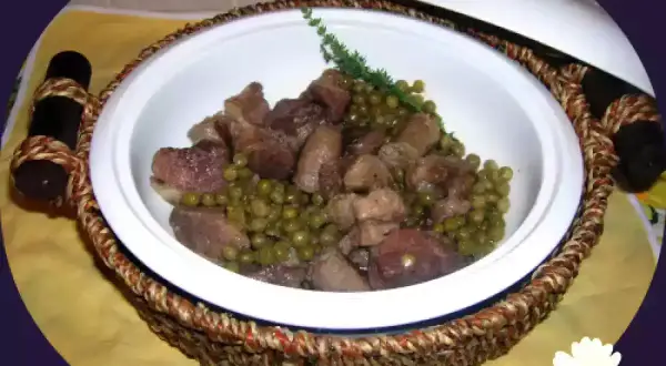 Un invitante spezzatino di maiale con piselli, servito in una ciotola bianca con manici intrecciati.