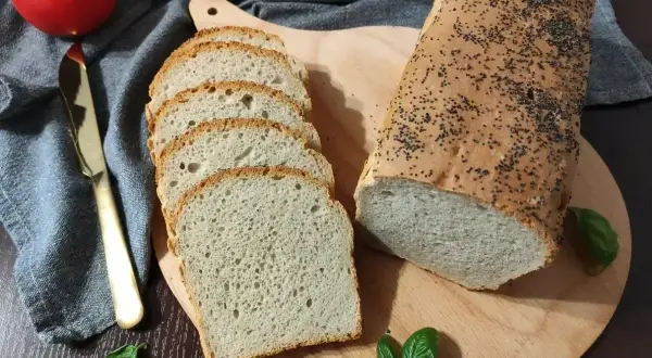 Domowy chleb pieczony w piekarniku, posypany makiem, pokrojony w kromki. Idealny przepis na pyszny, świeży bochenek.