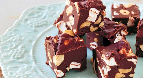 Chokladbitar med marshmallows och nötter, en härlig rocky road-fudge på en ljusblå tallrik.