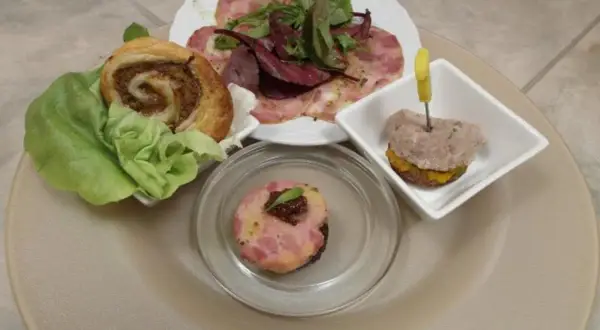 Verschiedene Tapas mit Fleisch: ein Fleischröllchen im Blätterteig, ein kleiner Burger mit Fleisch und ein Stück Fleischpastete.