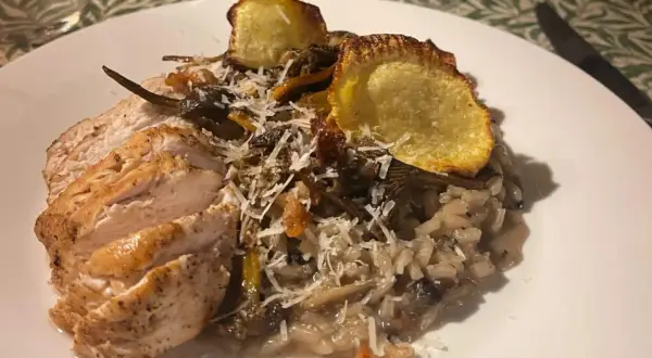 En härlig tallrik med tryffelrisotto med kyckling, toppad med krispiga potatisskivor och riven parmesan. En riktig smakupplevelse!