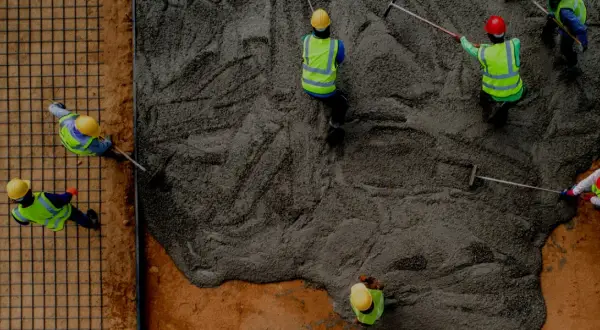 Pracownicy wylewają beton na strop monolityczny. Kluczowe są wymagania konstrukcyjne dla betonu B20 lub B25.