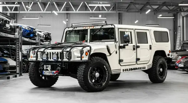 Biały Hummer H1 z potężnymi oponami i dodatkowym oświetleniem na dachu, gotowy na każdą przygodę.
