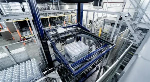 Automatyczny system pakowania butelek z wodą w nowoczesnym gnieździe produkcyjnym.