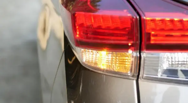 Gros plan sur le feu arrière d'une voiture, le clignotant jaune est allumé, prêt à indiquer un changement de direction.