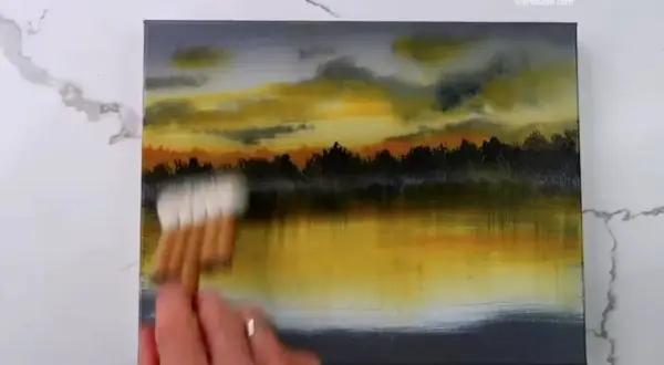 Peinture au scotch d'un paysage au coucher du soleil, avec des nuages orangés et jaunes reflétés dans l'eau.