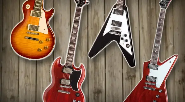 Vier ikonische Gibson Gitarren Modelle: eine Les Paul, SG, Flying V und Explorer, auf Holz Hintergrund.