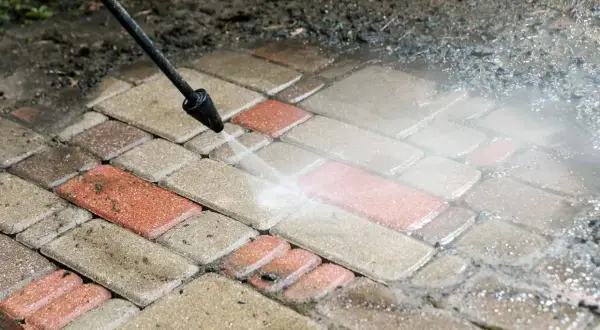 Mycie kostki brukowej myjką ciśnieniową. Woda pod ciśnieniem skutecznie usuwa brud, pokazując, czym wyczyścić kostkę brukową.