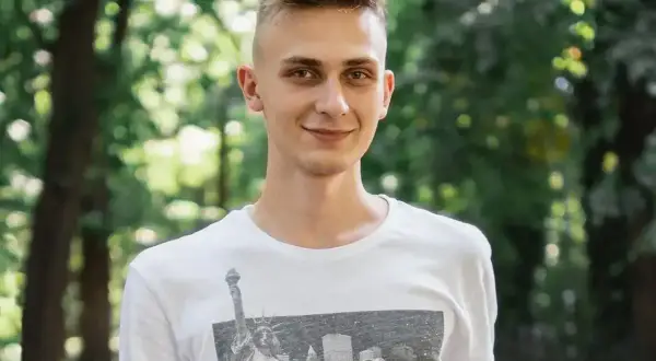 Uśmiechnięty nastolatek w białej koszulce z widokiem na Nowy Jork. Może to być przykład, jak zespół Aspergera objawy u nastolatków mogą być subtelne.