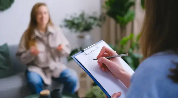 Psycholog policyjny zarobki: sesja terapeutyczna z pacjentem, notatki na kartce.
