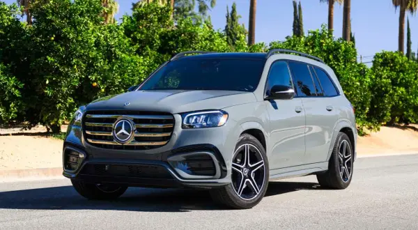 Szary Mercedes-Benz GLS na tle zieleni. Elegancki SUV z charakterystycznym grillem i felgami.