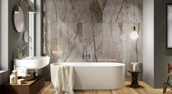 Bagno moderno con vasca freestanding, lavabo sospeso e parete in marmo con venature che si abbinano al legno del pavimento. Idee bagno marmo e legno per un ambiente di lusso.