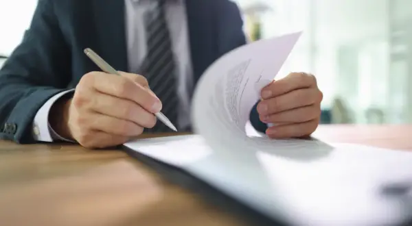 Biznesmen podpisuje dokument, który może być pełnomocnictwem szczególnym.
