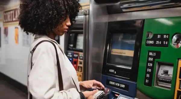 Kobieta z burzą włosów dokonuje płatności na stacji metra, korzystając z bankomatu. To jej millenium wypłata z innego bankomatu, bo ten jest bliżej.