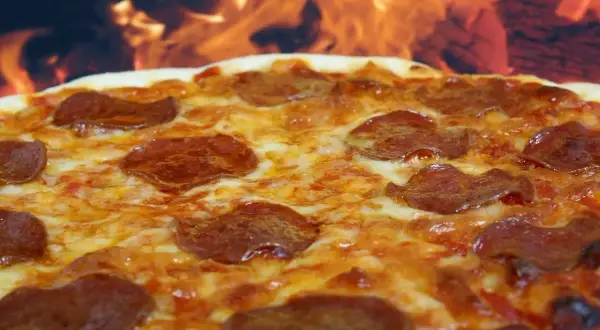 Pyszna pepperoni pizza z ciągnącym się serem, pieczona w ogniu.