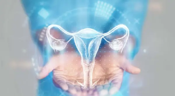 Dłoń trzymająca świecący hologram narządów rodnych kobiety. Grafika może symbolizować zapalenie przydatków objawy i potrzebę diagnostyki.