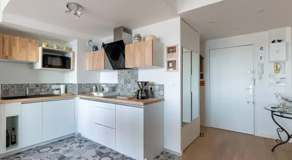 Cuisine 10m2 fermée, moderne et fonctionnelle avec placards blancs, carrelage géométrique et plan de travail en bois.