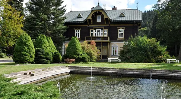 Urokliwy dworek w Karlovej Studance z basenem i fontannami, otoczony zielenią.