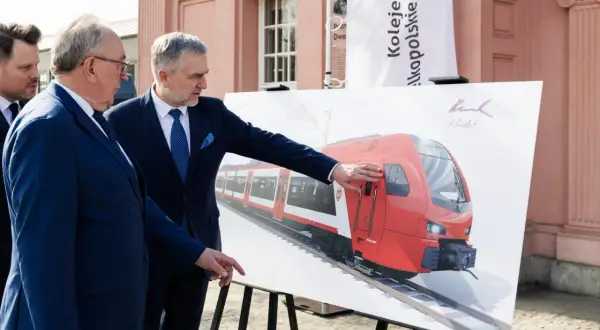 Dwóch mężczyzn w garniturach ogląda wizualizację nowego pociągu Kolei Wielkopolskich. Nowe połączenia Poznań - Nowy Tomyśl wkrótce!