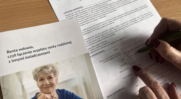 Uśmiechnięta starsza pani na zdjęciu obok formularza ZUS. Dokument dotyczy ustalenia zbiegu świadczeń z rentą rodzinna, czyli co to jest renta rodzinna.