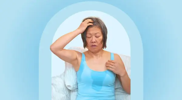 A woman experiencing night sweats after working out, with sweat visible on her tank top and forehead.