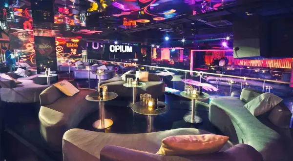 Interni lussuosi della discoteca Opium a Barcellona, con divani curvi, tavolini di vetro e luci al neon che creano un'atmosfera vibrante.