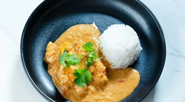 En krämig butter chicken med ris, garnerad med färsk koriander. En smakrik indisk rätt.