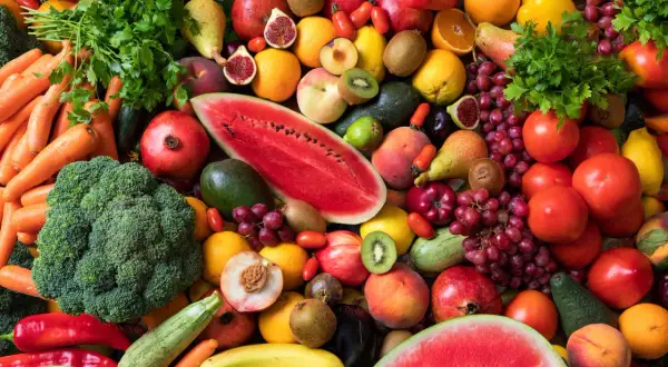 Bunte Vielfalt an Obst und Gemüse: Karotten, Brokkoli, Wassermelone, Trauben, Tomaten, Orangen, Kiwis, Pfirsiche und mehr. Eine Inspiration, wieviel Obst am Tag gesund ist.
