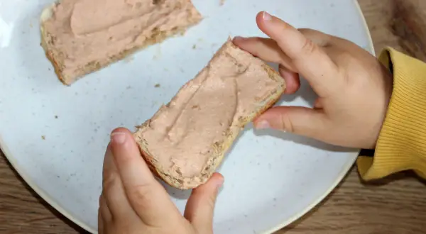 Kind hält Brot mit Leberwurst. Ab wann Leberwurst Baby? Erste Kostprobe für den Nachwuchs.