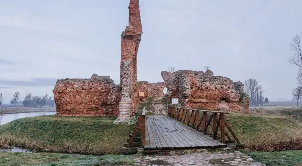 Ruiny zamku w Uniejowie, jedna z ciekawych województwo łódzkie atrakcje, z drewnianym mostkiem prowadzącym do wnętrza.