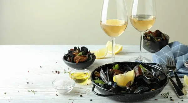 Ein festliches Essen: Muscheln mit Zitrone und Kräutern, dazu ein Glas Weißwein. Perfekt für einen genussvollen Abend.