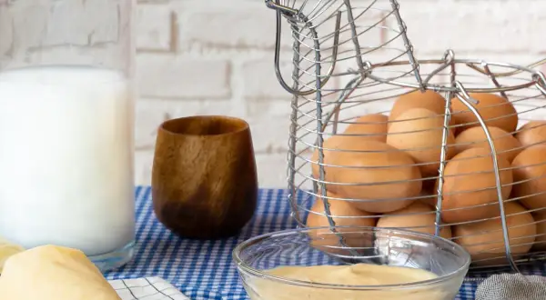 Crema pastelera lista para usar, hecha con Thermomix. Huevos frescos en cesta de gallina, leche y un toque de madera.