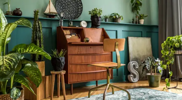Wnętrze w stylu retro: drewniane biurko, krzesło, rośliny i dekoracje tworzą przytulną atmosferę.