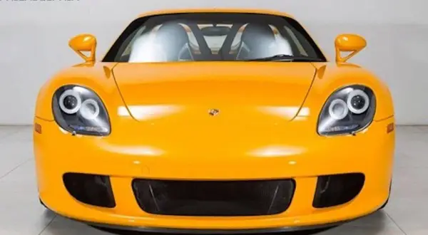 Pomarańczowy Porsche Carrera GT z charakterystycznymi okrągłymi światłami i sportowym grillem.