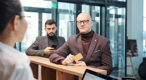 Mężczyzna z kartą w ręku, spełniający wymagania private banking, czeka przy ladzie.