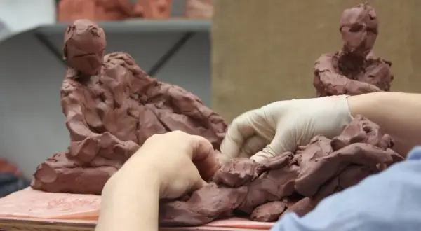 Hands sculpt clay figures, a glimpse into the dedication needed for the best sculpture schools.