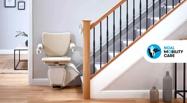 Installazione montascale beige su una scala con corrimano in legno e ringhiera nera. La soluzione ideale per la mobilità in casa.