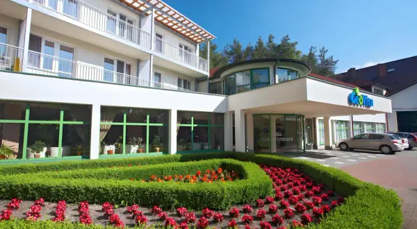 GeoVita Dąbki cennik: nowoczesny budynek hotelowy z zadbanym ogrodem i kwiatami.