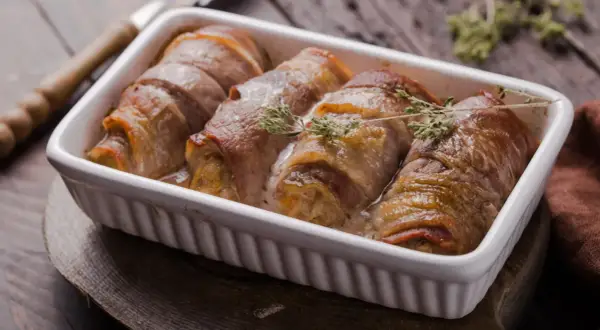 Roladki schabowe pieczone w naczyniu, zawinięte w boczek, z gałązkami tymianku.