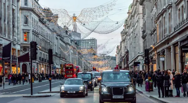 Świąteczne iluminacje nad ulicą w Londynie, z charakterystycznym czarnym taksówką i czerwonym autobusem. Piccadily Circus w całej okazałości.