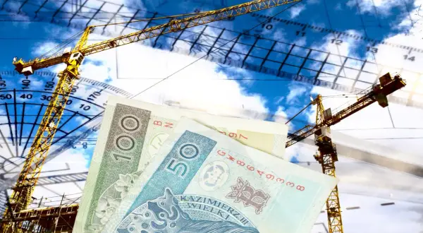 Ile kosztuje podział domu przez geodetę? Żurawie budowlane, plany i polskie banknoty symbolizują koszty inwestycji.