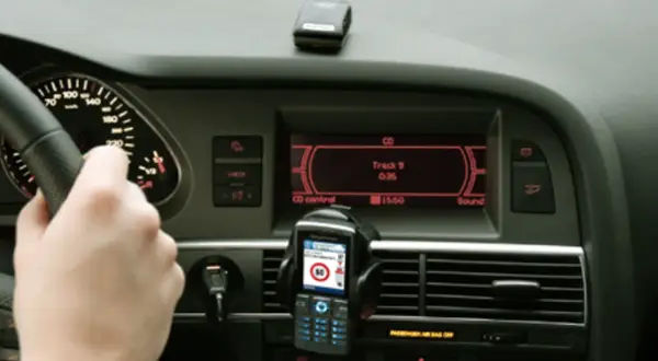 Ręka na kierownicy, telefon z nawigacją i ekran radia w samochodzie. Czy to podpowiedź, jak odkodować radio?