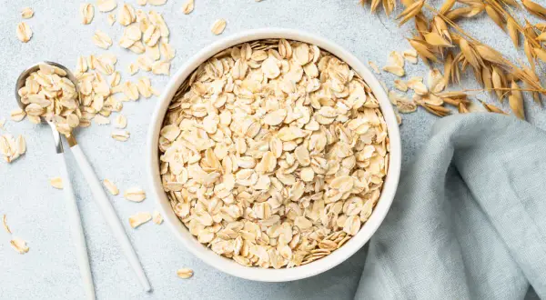 Misternie ułożone płatki owsiane w misce i na łyżce. Czy płatki owsiane mają gluten? Zwykłe płatki owsiane nie zawierają glutenu, ale mogą być zanieczyszczone podczas przetwarzania.