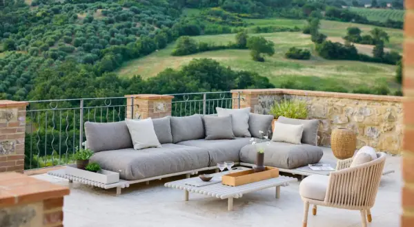 Eine stilvolle Dachterrasse gestalten: Gemütliche Lounge-Möbel mit Blick auf grüne Hügel laden zum Entspannen ein.