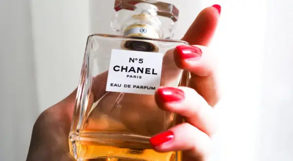 Dłoń z czerwonymi paznokciami trzyma flakonik Chanel N°5 100ml.