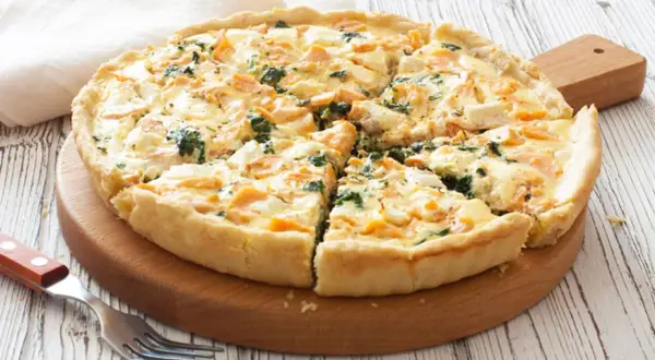 Tarta de espinacas y salmón, recién horneada y cortada en porciones, lista para disfrutar.